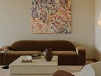 Living room with a brown sofa, coffee table, and abstract painting on the wall.