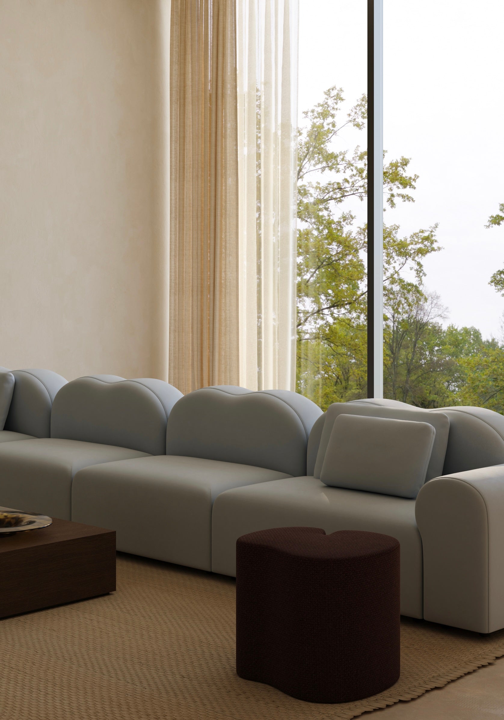 Gray sectional sofa in a living room with large windows and curtains.